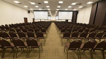 A conference room with rows of chairs facing a large screen at the front.