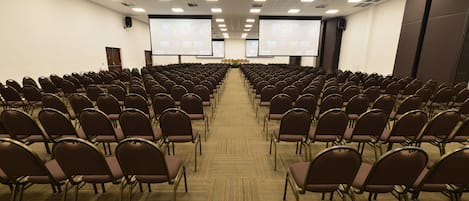 A conference room with rows of chairs facing a large screen at the front.