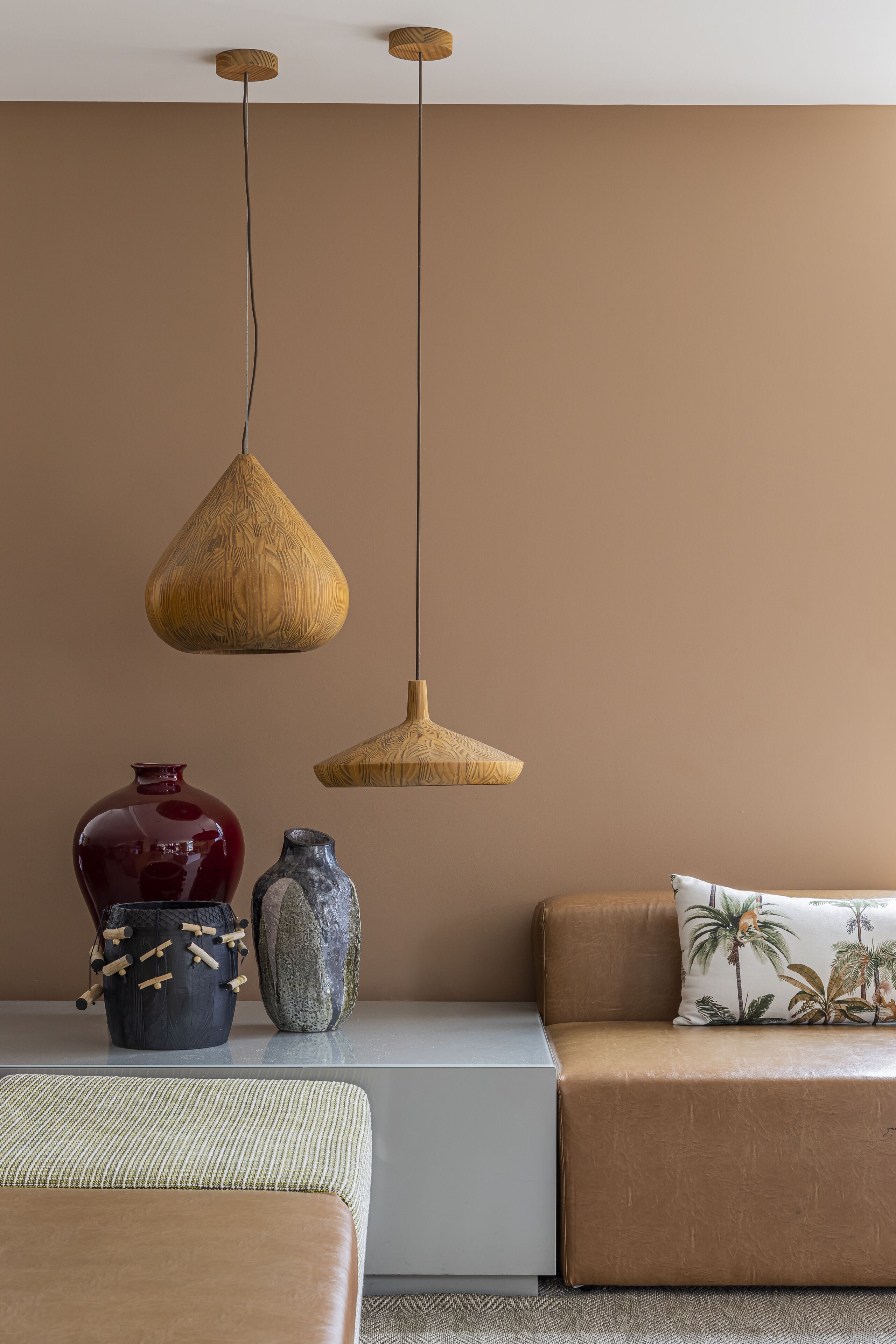 Un salon moderne avec un canapé, deux lampes suspendues et des vases décoratifs.
