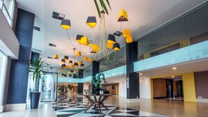 Un vestíbulo amplio con suelo a cuadros, iluminación colgante moderna y una mesa central con sillas.