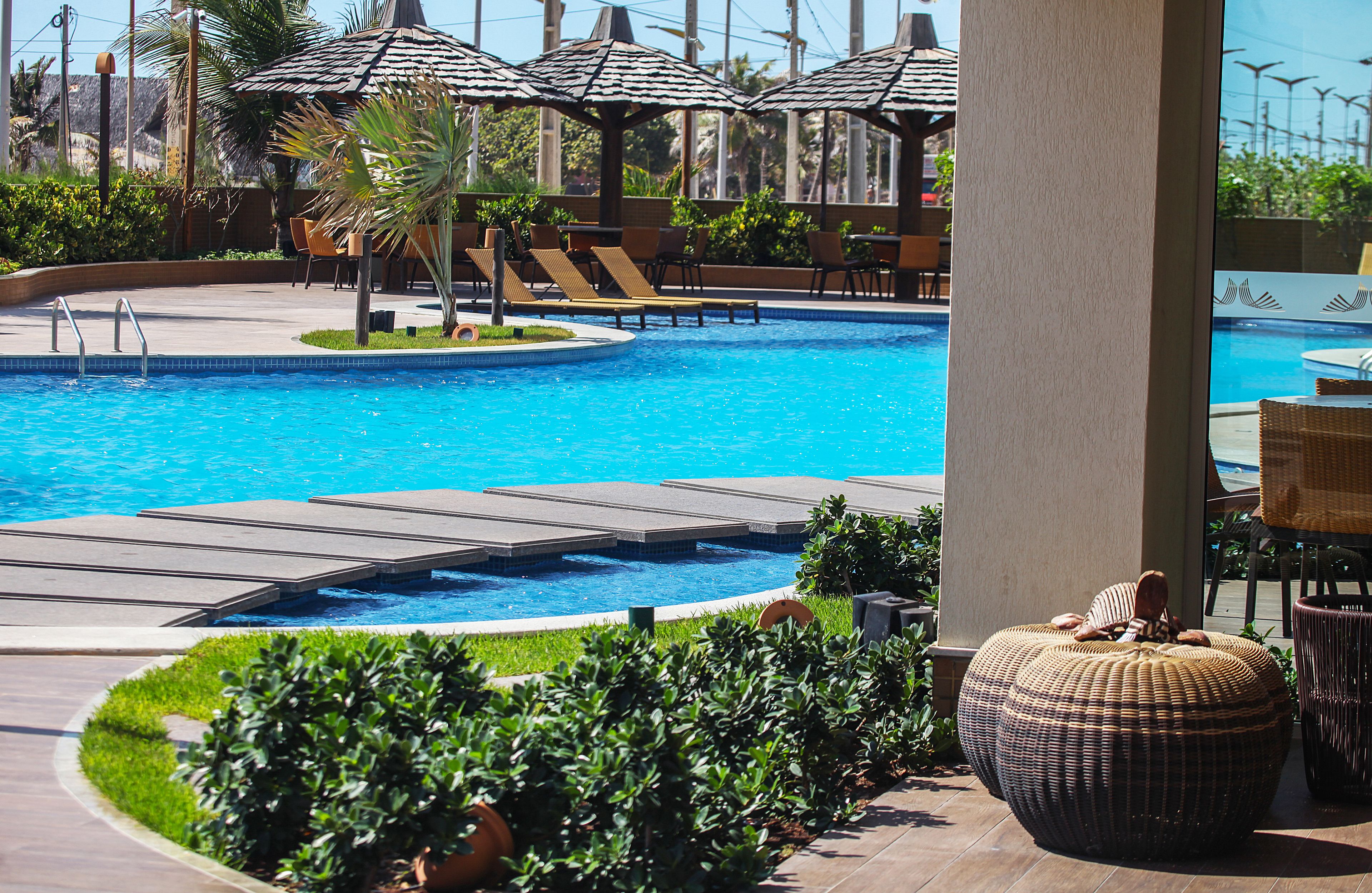 Zona de piscina con sillones, sombrillas y vista al océano.