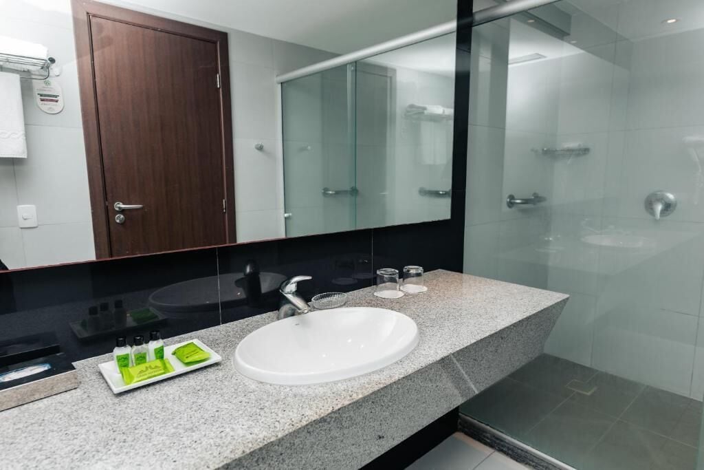 A modern bathroom with a granite countertop, a white sink, and a glass shower enclosure.