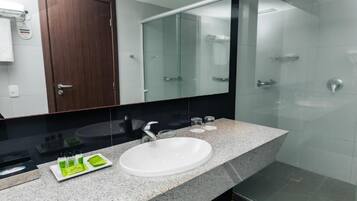 A modern bathroom with a granite countertop, a white sink, and a glass shower enclosure.