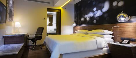 Una habitación de hotel moderna con una cama grande, un escritorio, una silla y una lámpara de escritorio.