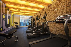 A gym with treadmills, elliptical machines, and a bench.