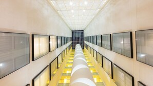 A modern interior with a central escalator, glass panels on the walls, and a patterned ceiling. - Krystal Urban Guadalajara (Guadalajara)