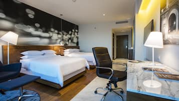 A modern hotel room with a large bed, two bedside tables, a desk with a chair, and a large wall mural.