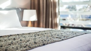 A hotel room with a bed, a lamp, and a view of the outdoors. - One88 On Commerce (Whakatane)