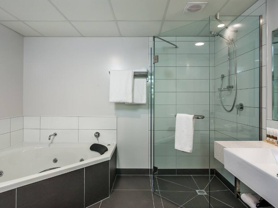 Un baño moderno con ducha envuelta en vidrio, una bañera independiente y un tocador con lavamanos.