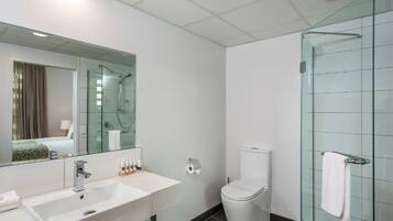 Une salle de bain moderne avec une douche à parois de verre, un lavabo blanc et des toilettes.