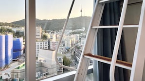 A cityscape view from a window with a white metal ladder leaning against the window frame. - Myeongdong Merlin Hotel (Seoul)