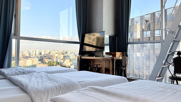 A hotel room with two beds, a TV, and a city view. - Myeongdong Merlin Hotel (Seoul)