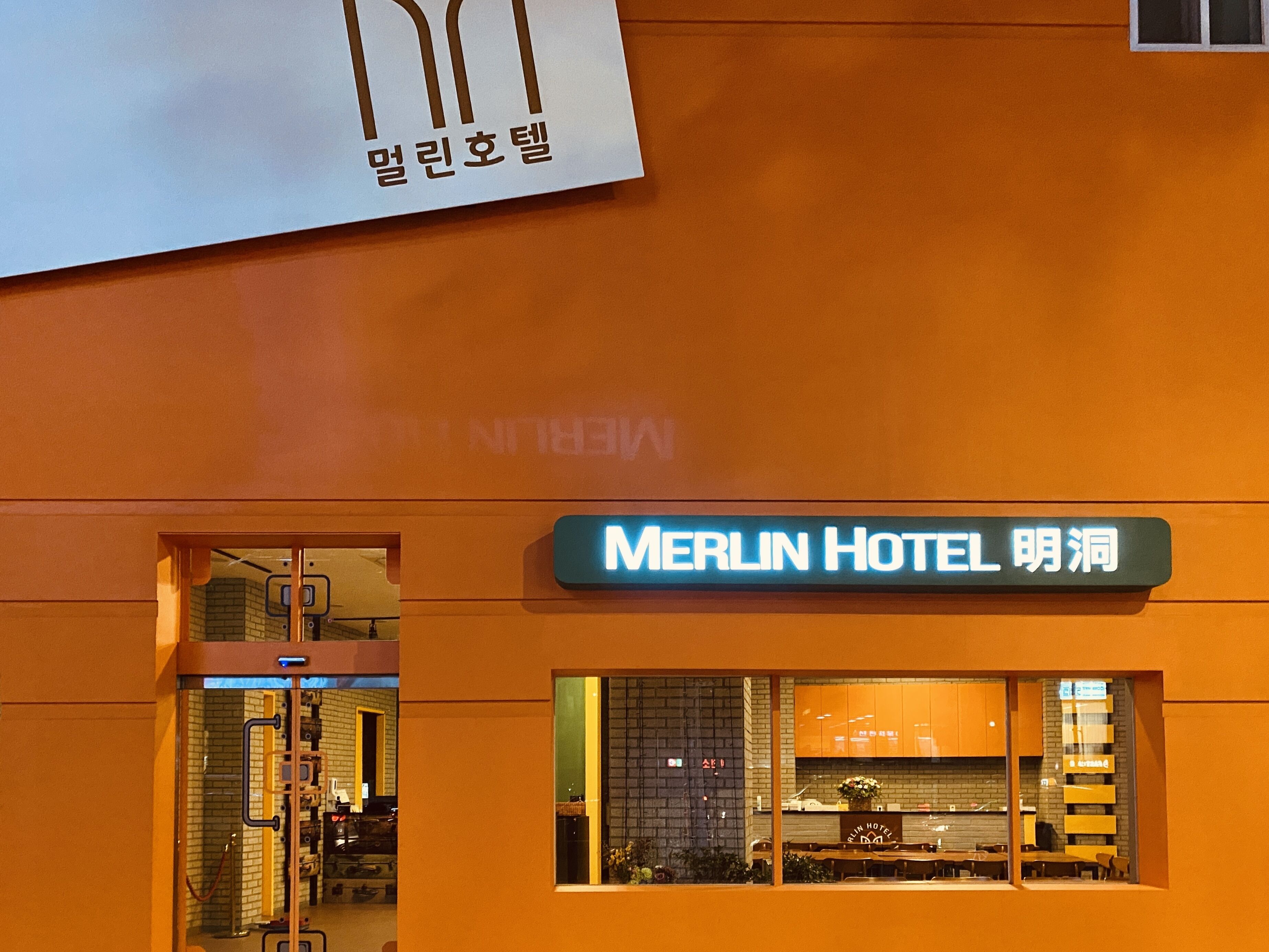 The exterior of the Merlin Hotel with a sign indicating its name.