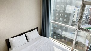 A hotel room with a bed, a window, and a view of a cityscape. - Myeongdong Merlin Hotel (Seoul)