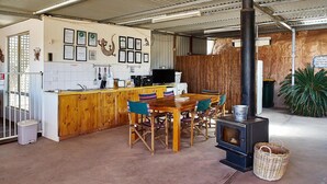 A rustic kitchen with wooden cabinets, a bar area, and a wood-burning stove. - Underground Bed and Breakfast (Coober Pedy)