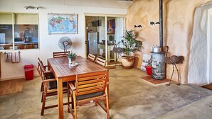 A dining area with a wooden table and chairs, a map on the wall, and a small fan. - Underground Bed and Breakfast (Coober Pedy)