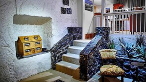 A staircase with a wooden house model, a chair, and a plant arrangement. - Underground Bed and Breakfast (Coober Pedy)