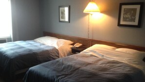 A hotel room with two beds, a bedside table with a lamp, and framed pictures on the wall. - Classic Inn (Melville)