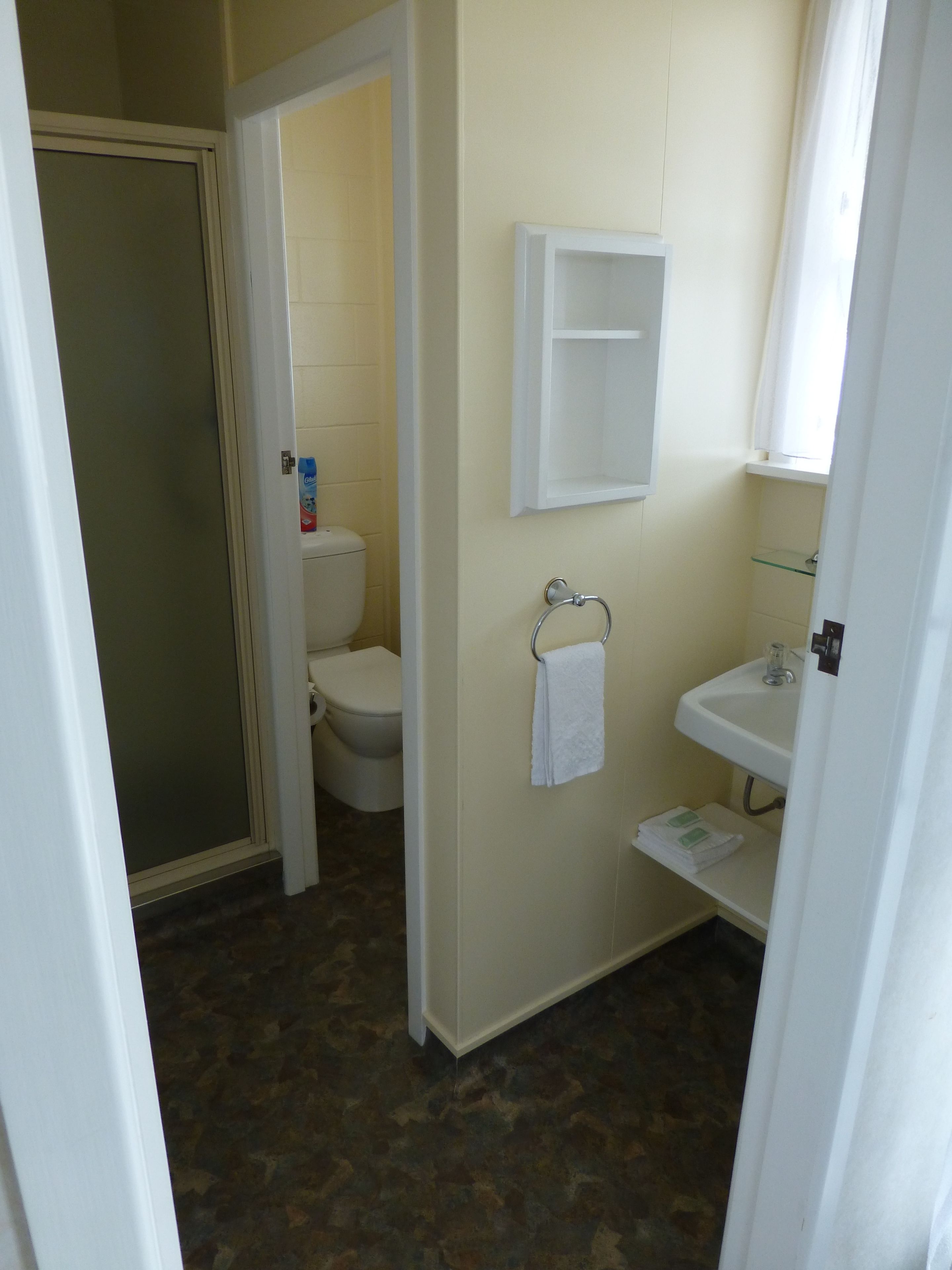 A bathroom with a toilet, sink, and a glass shower enclosure.