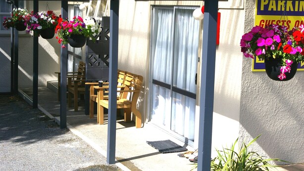 Un espace extérieur aménagé, abrité et doté de bancs en bois et de jardinières suspendues.