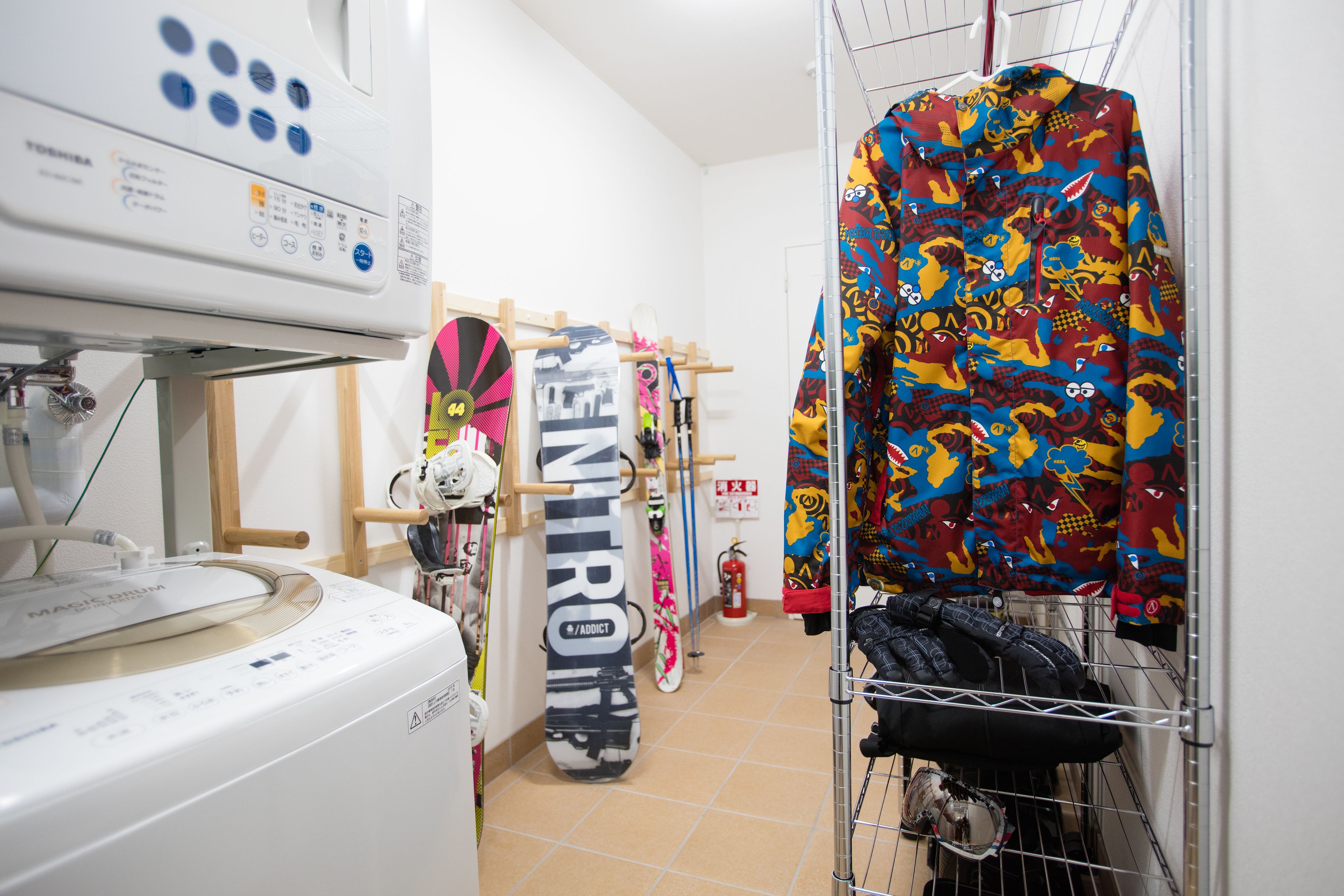 A laundry area with a washing machine, a drying rack, and a fire extinguisher.