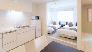 A compact hotel room with a kitchenette, two beds, and a small bathroom. - Bliss Lodging (Kutchan)