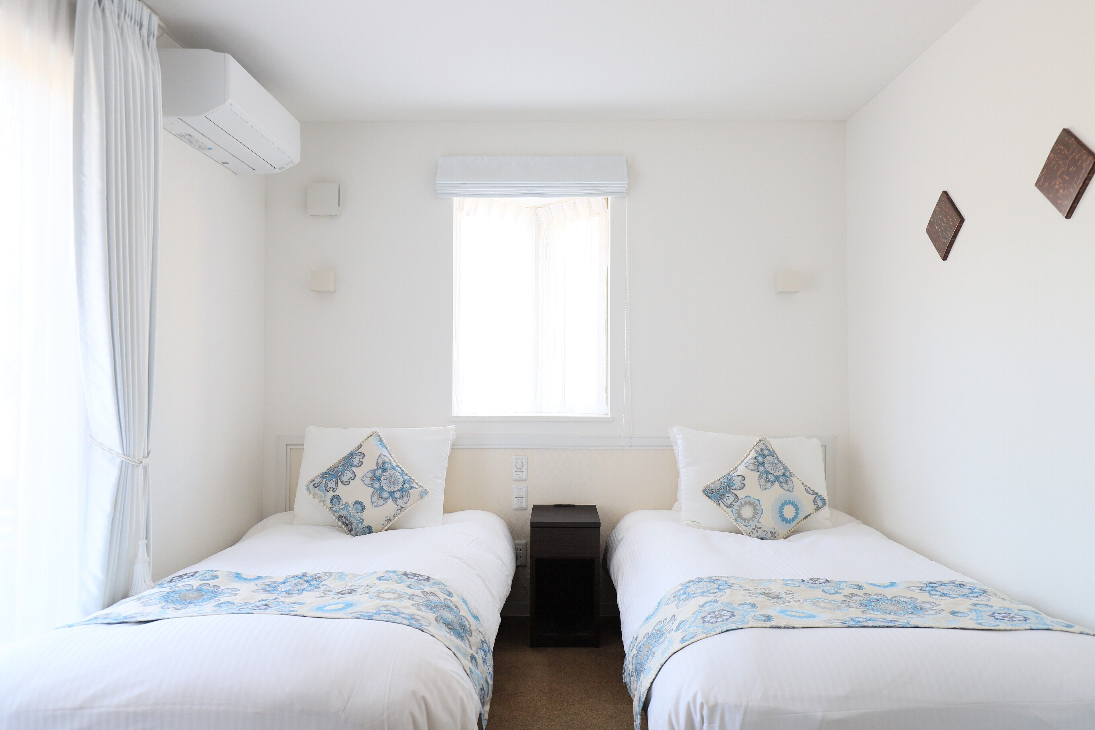 A room with two beds, a window, and a small table between them.