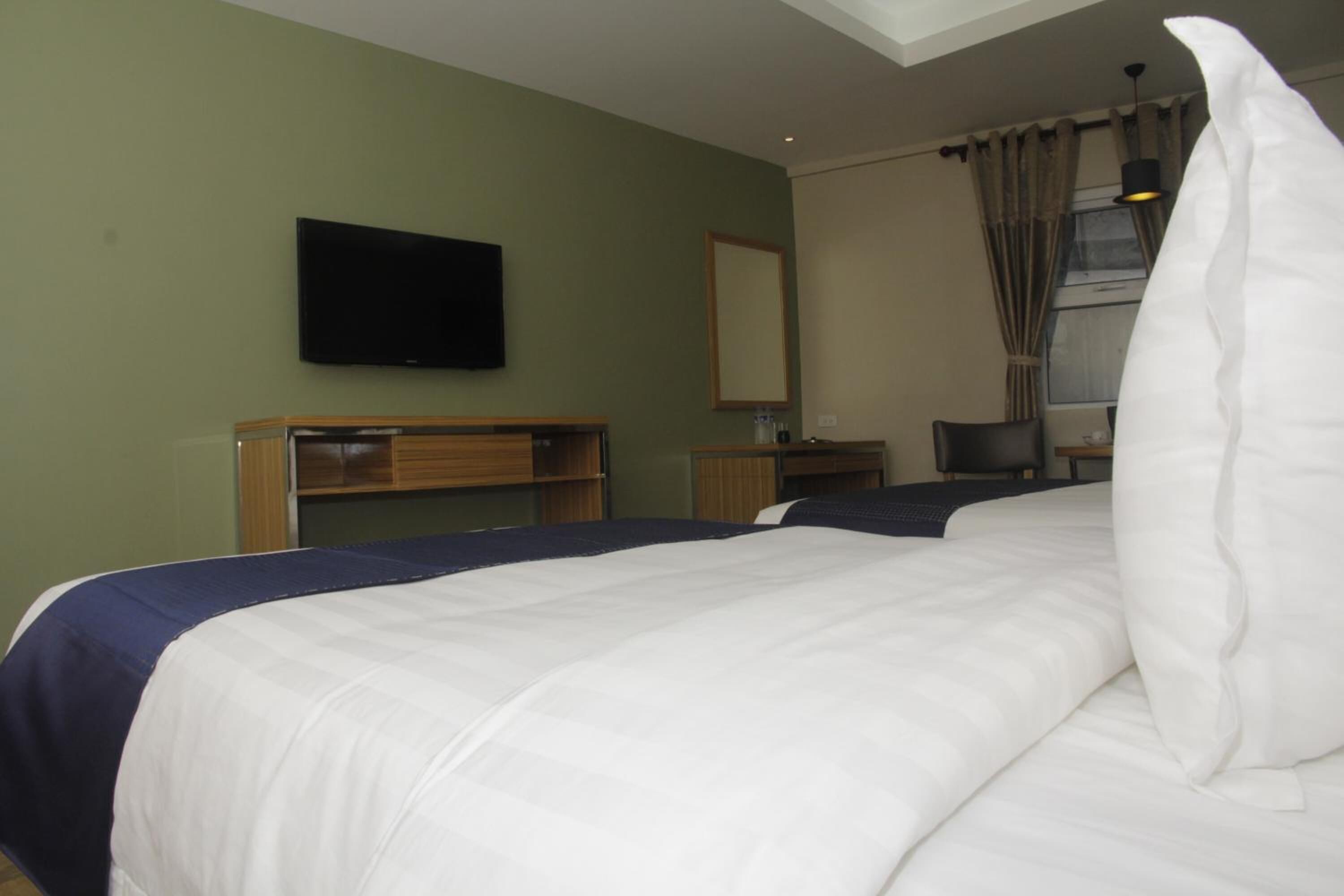 A hotel room with a bed, a TV mounted on the wall, a desk, and a chair.