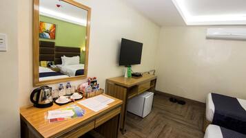 Une chambre d’hôtel avec un bureau en bois, un lit, une télévision et un petit réfrigérateur.