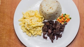 Un plato con arroz, huevos revueltos, carne de res y verduras mixtas.
