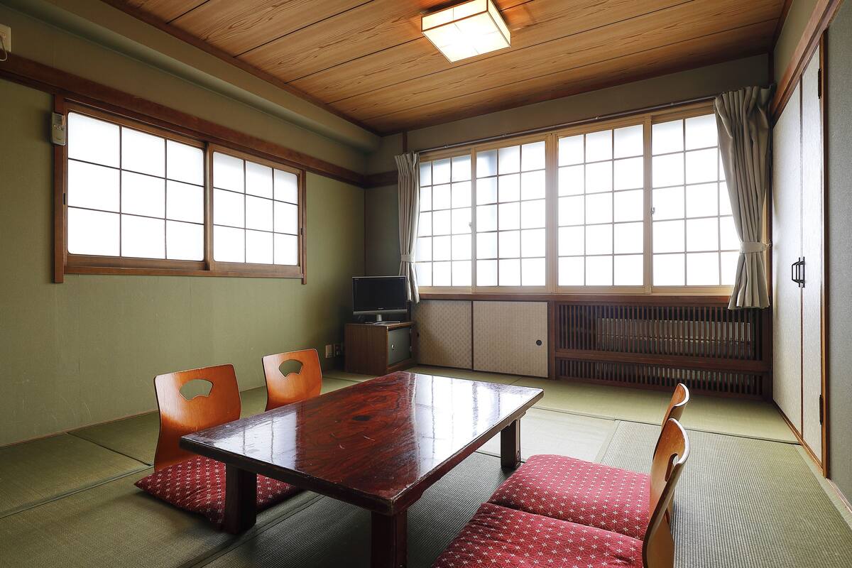 Um quarto japonês tradicional com tatames, uma mesa de madeira baixa e portas deslizantes.