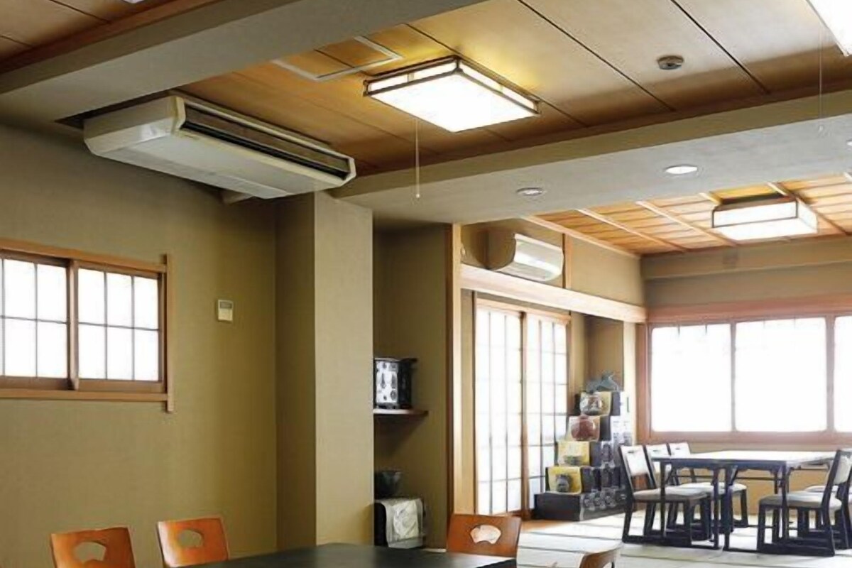 Una habitación con esteras de tatami, una mesa tradicional japonesa y sillas.