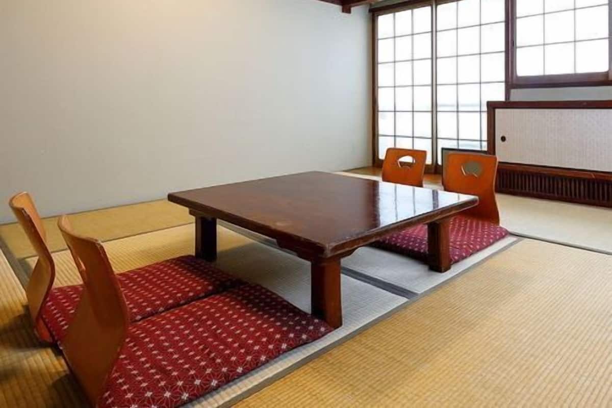 Um quarto japonês tradicional com tatames, uma mesa de madeira baixa e painéis shoji.