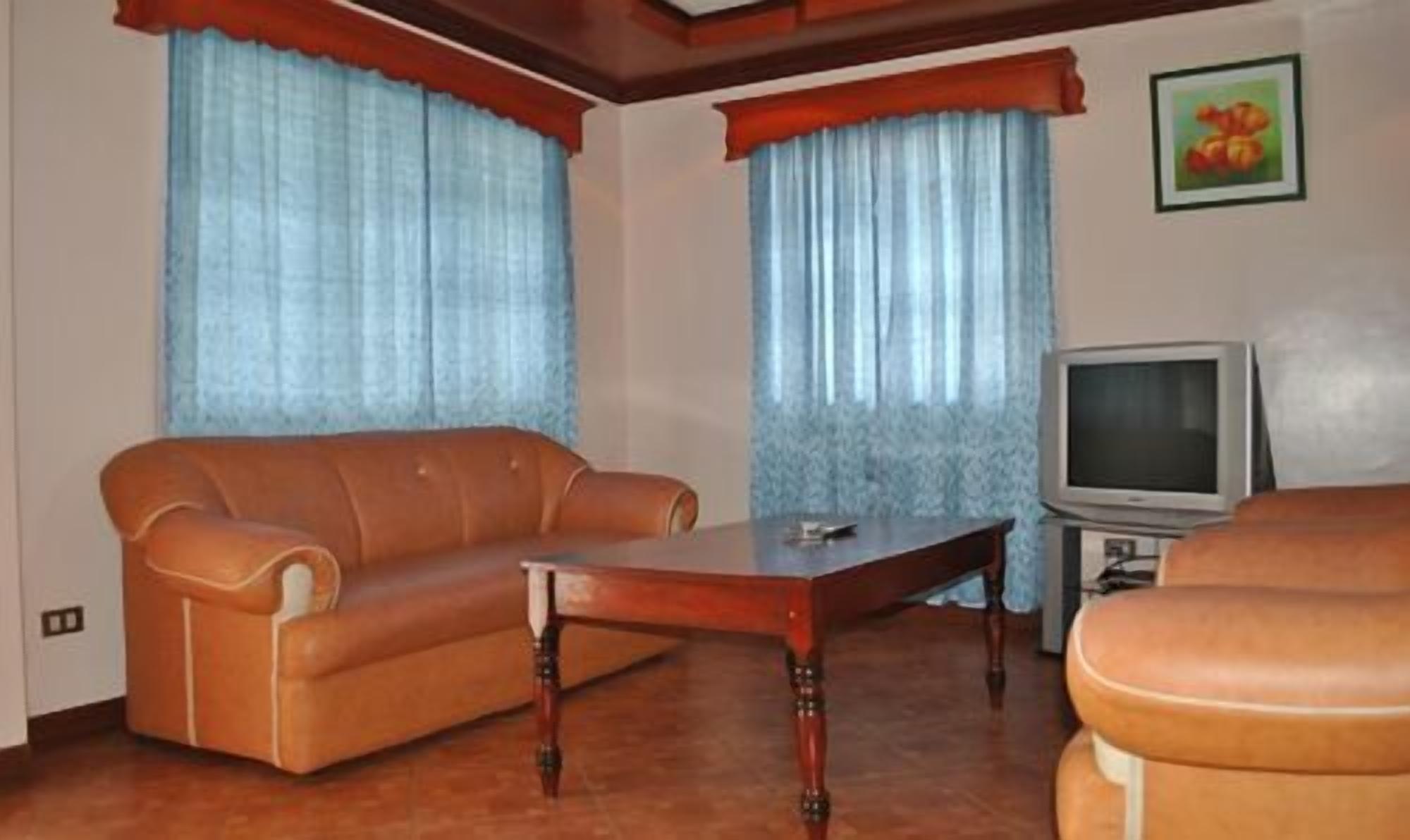 A living room with a brown leather sofa, a wooden coffee table, and a television on a stand.
