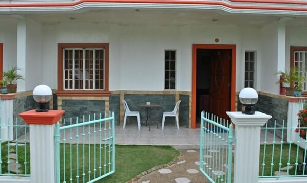 A building with a covered patio area, white chairs, and a small table. - Datag Cordova Home Village (Cordova)