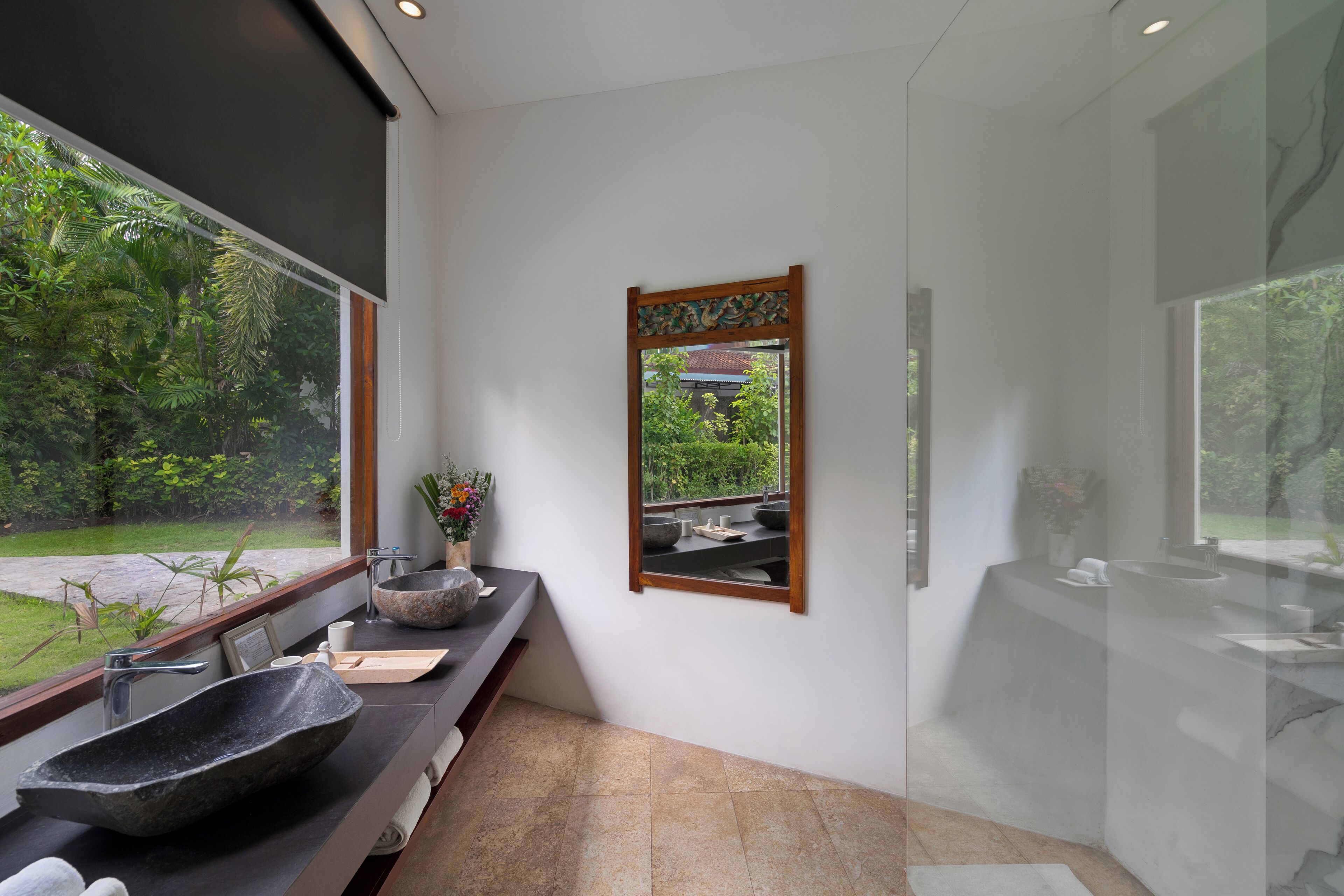 A modern bathroom with a large window, a stone sink, and a mirror.