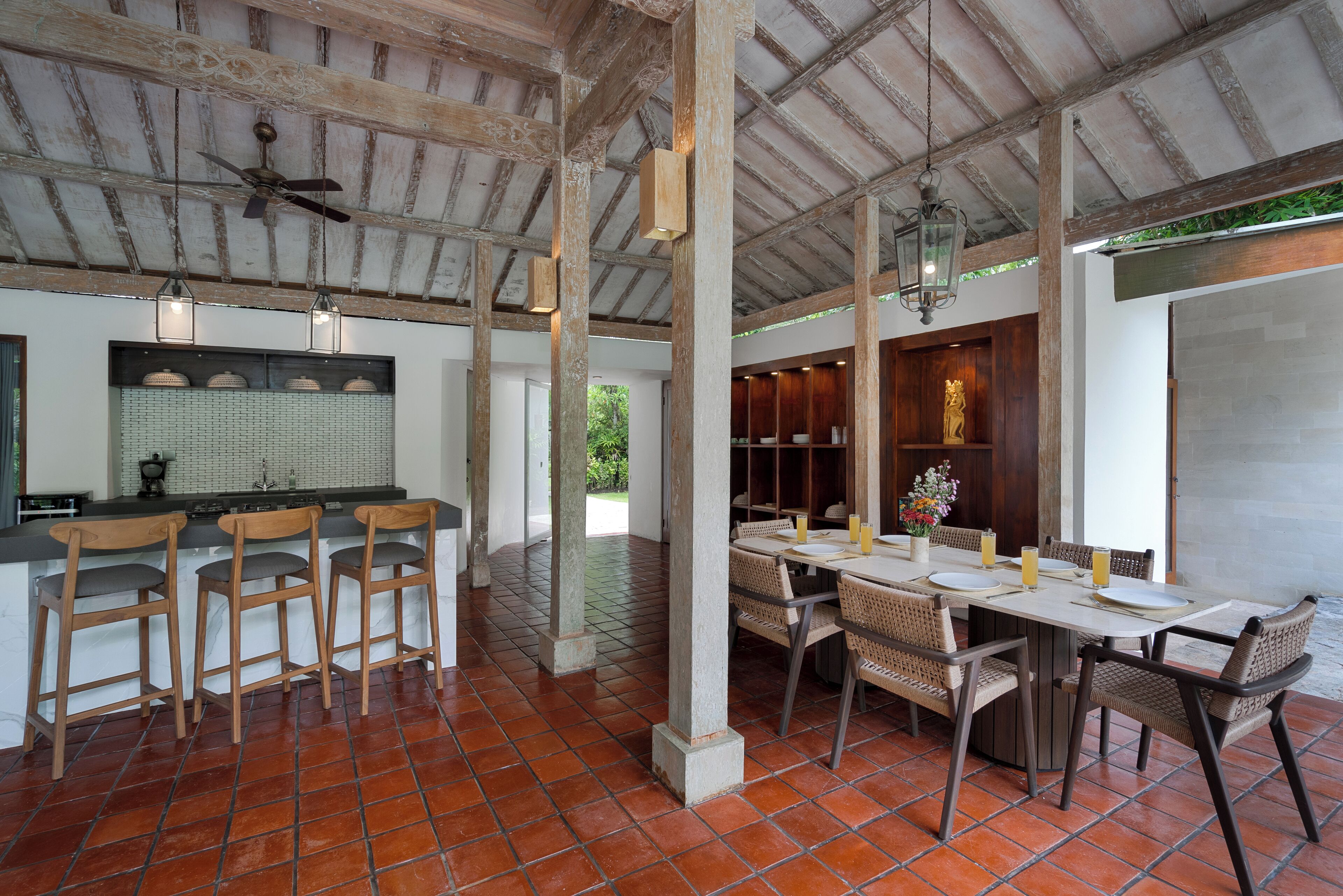 Un'ampia sala da pranzo con soffitto alto, travi a vista e pavimento piastrellato.