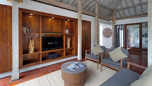 Amplia sala de estar con mueble de entretenimiento de madera, televisor de pantalla plana y asientos cómodos.