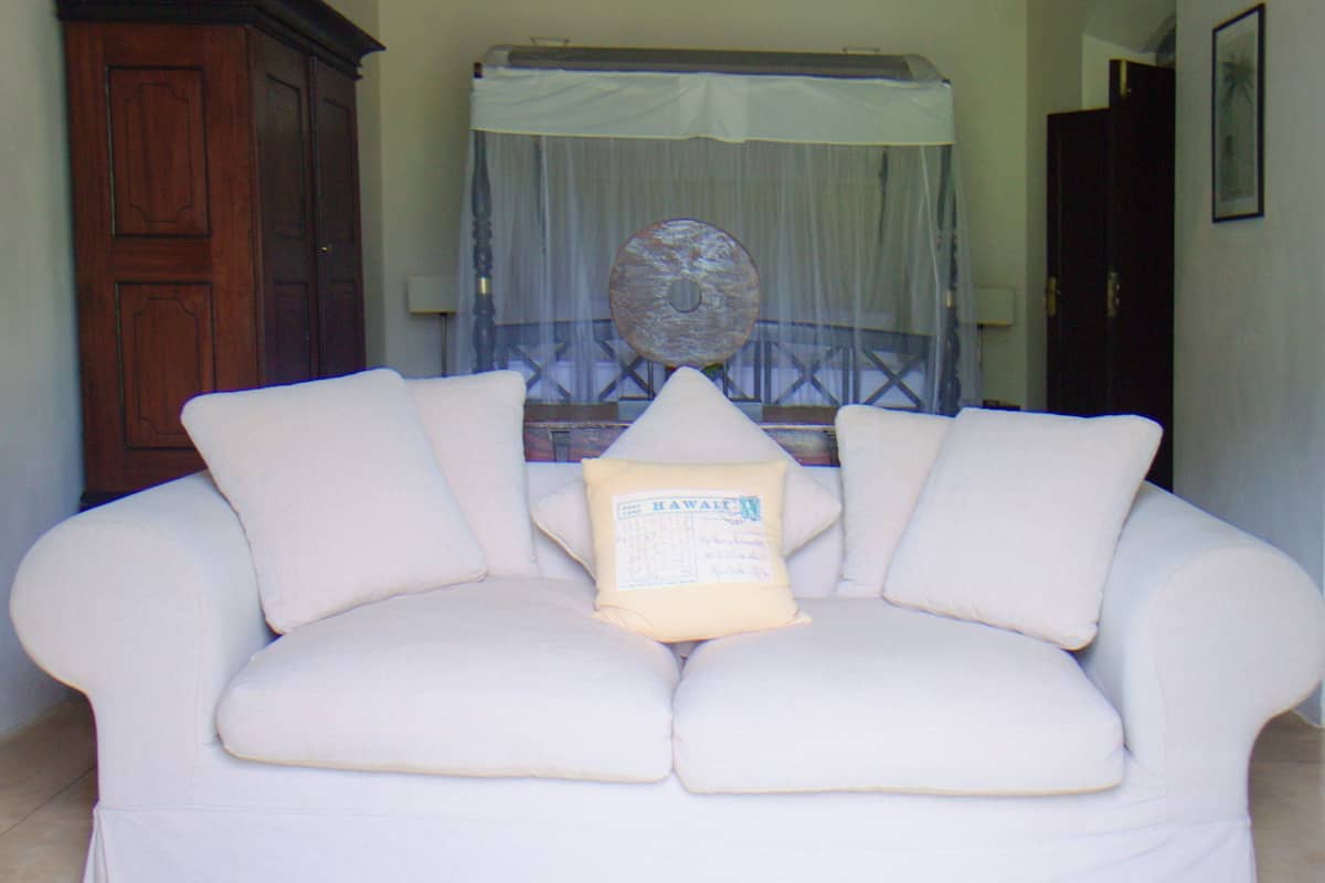 A white sofa with a pillow, a wooden cabinet, and a ceiling fan in a room with an arched doorway.