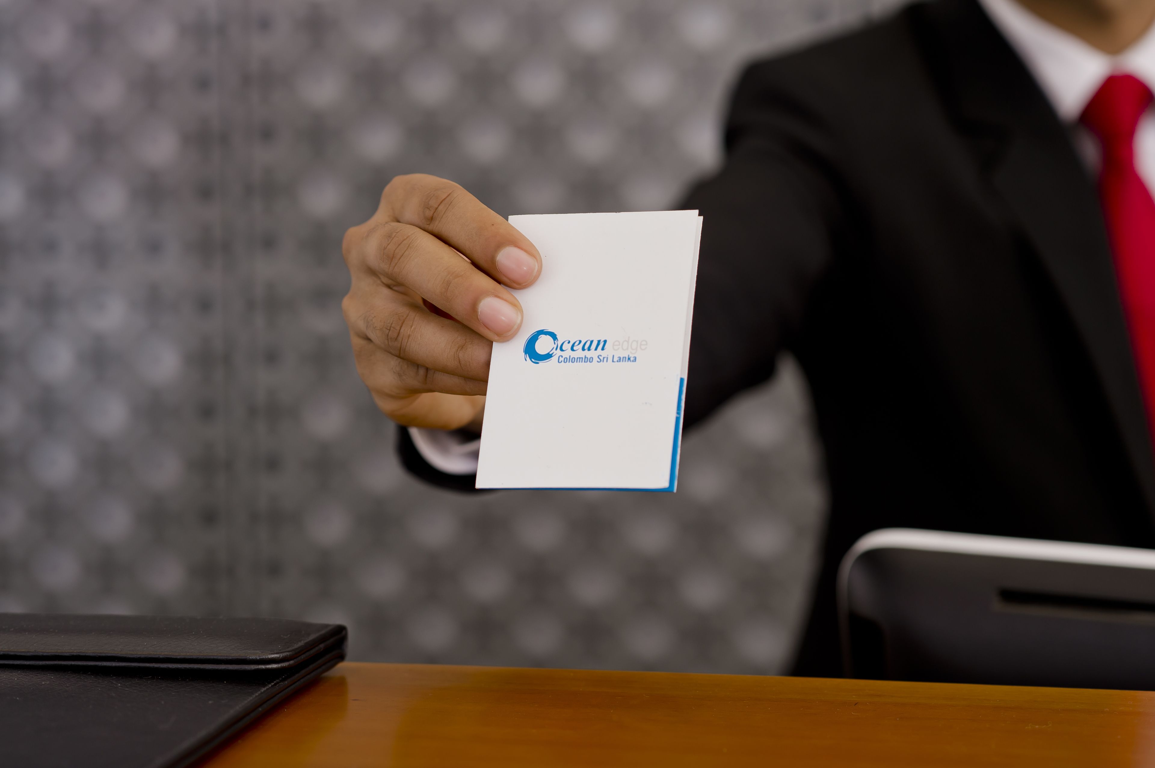 A person holding a business card with "Ocean Edge Colombo Sri Lanka" printed on it.