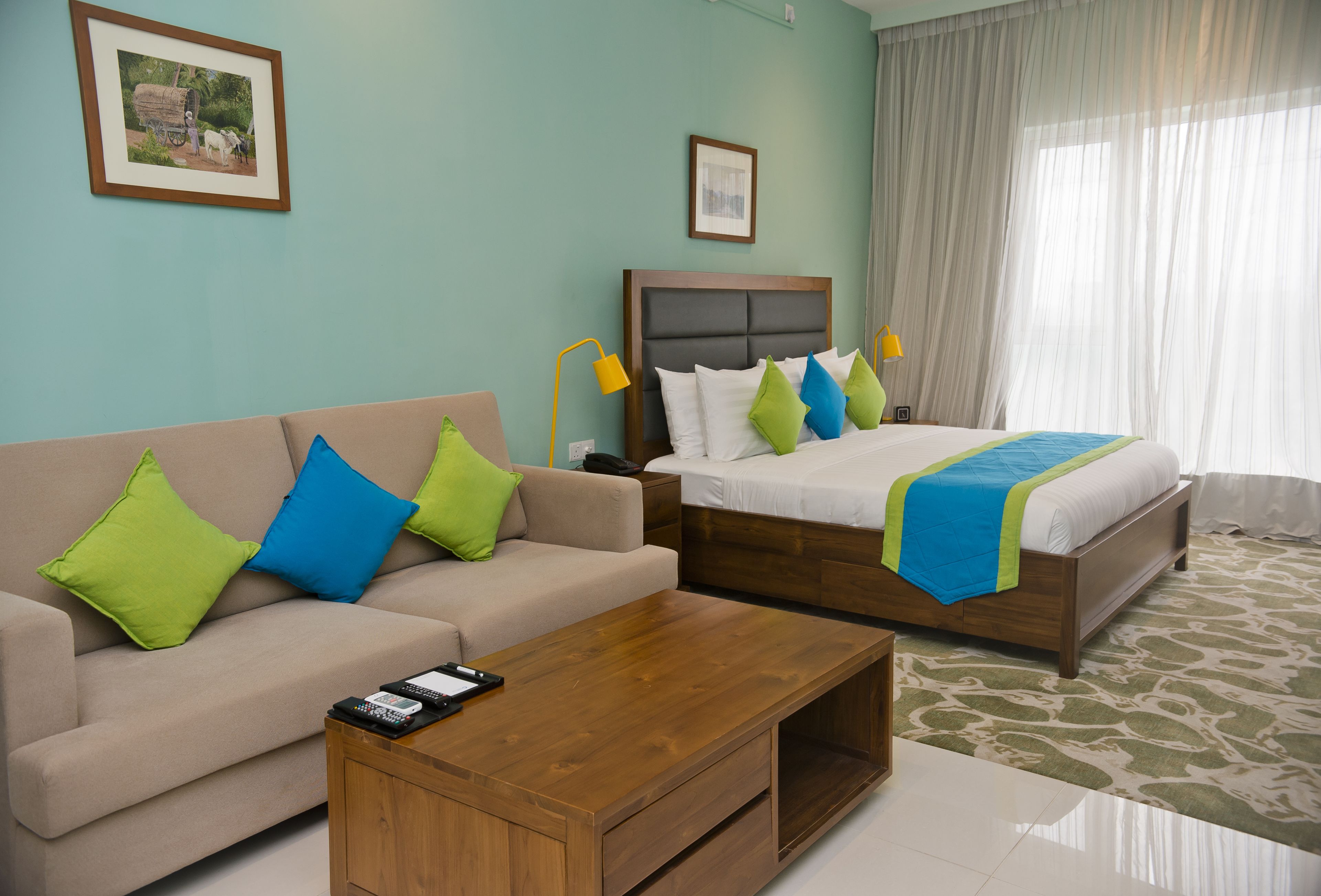A hotel room with a bed, a sofa, a coffee table, and a nightstand.