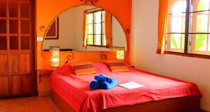 Una stanza con un letto grande, una porta in legno, uno specchio e una finestra con tende.