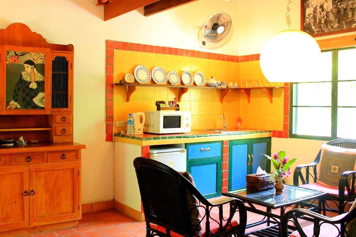 A compact kitchen with wooden cabinets, a microwave, and a dining area with a table and chairs.
