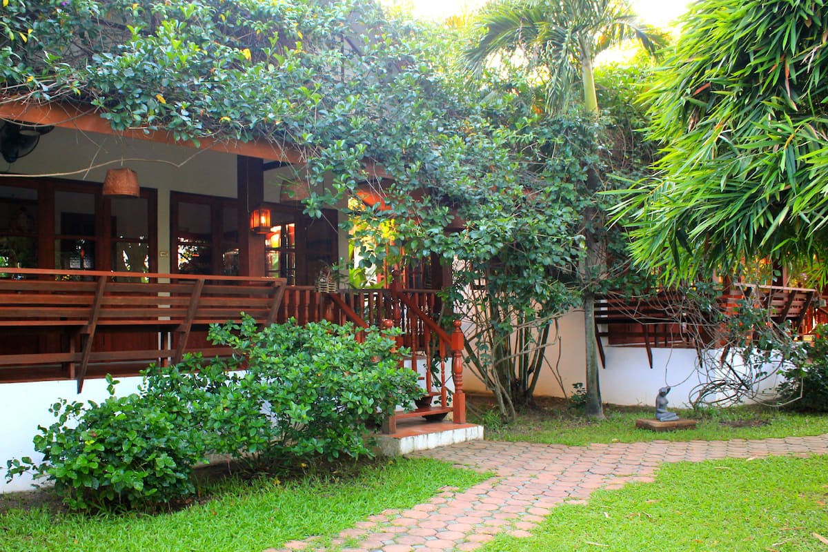 A courtyard with a wooden bench, a stone pathway, and lush greenery.