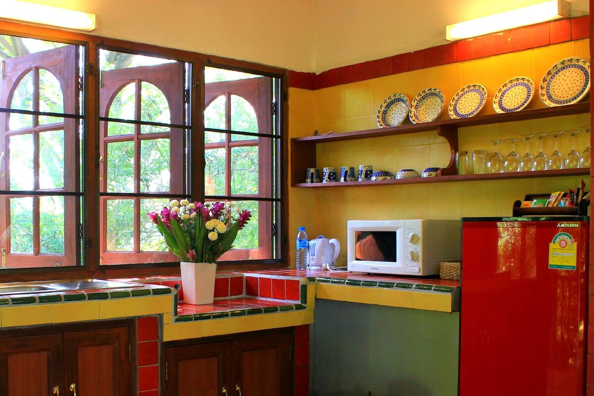 A kitchen with a window, a microwave, and a refrigerator.