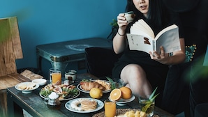 A person sitting at a wooden table with various breakfast items, including eggs, toast, and fruit. - Aspira D'Andora Sukhumvit 16 - Asoke (Bangkok)