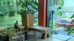 A reception area with a wooden bench, wicker stools, and potted plants. - Aspira D'Andora Sukhumvit 16 - Asoke (Bangkok)