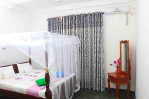 Un dormitorio ordenado con cama, mesita de noche, espejo y cortina.