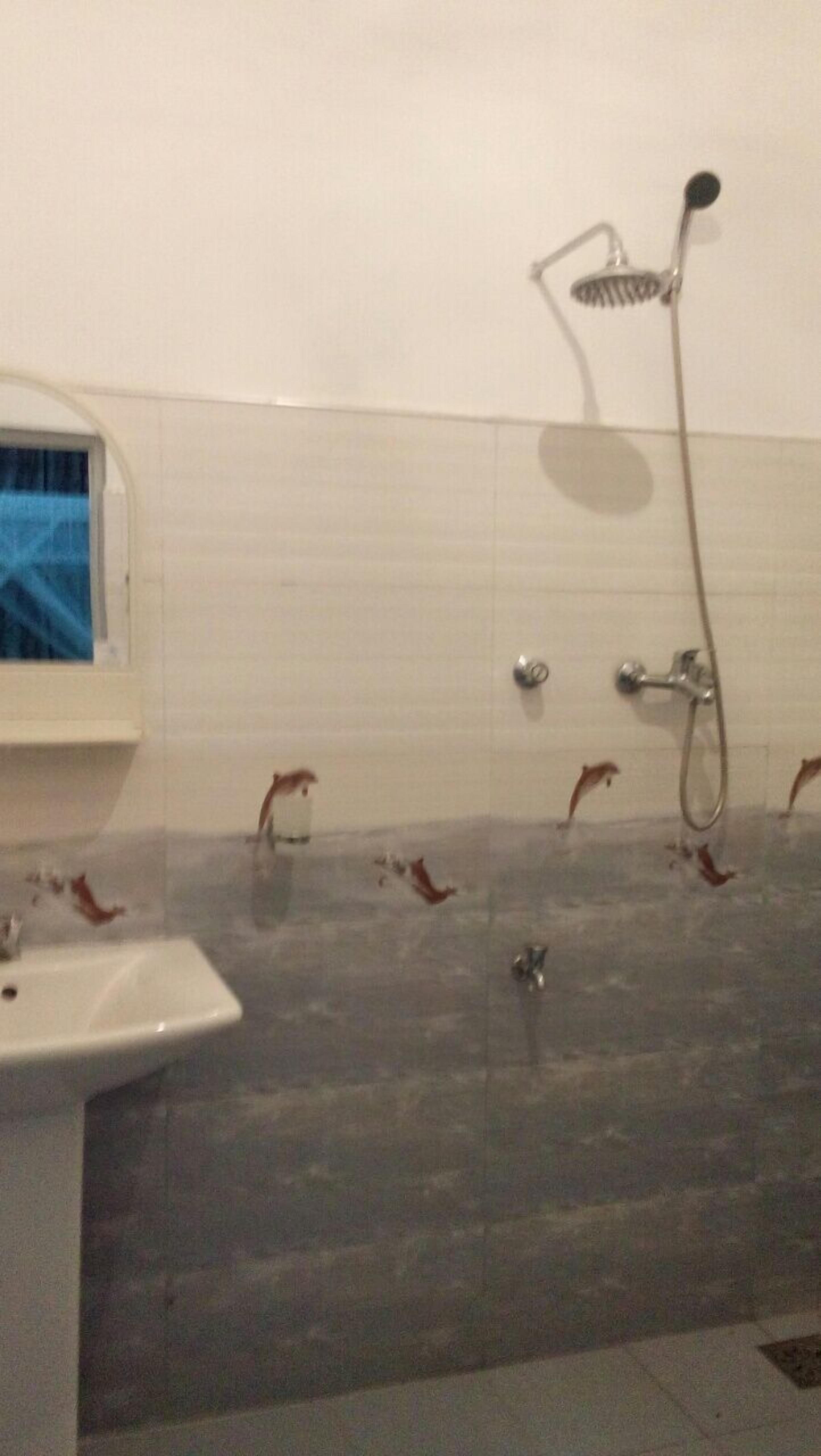Une salle de bain avec un lavabo, une douche et un mur carrelé.