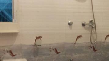 Une salle de bain avec un lavabo, une douche et un mur carrelé.